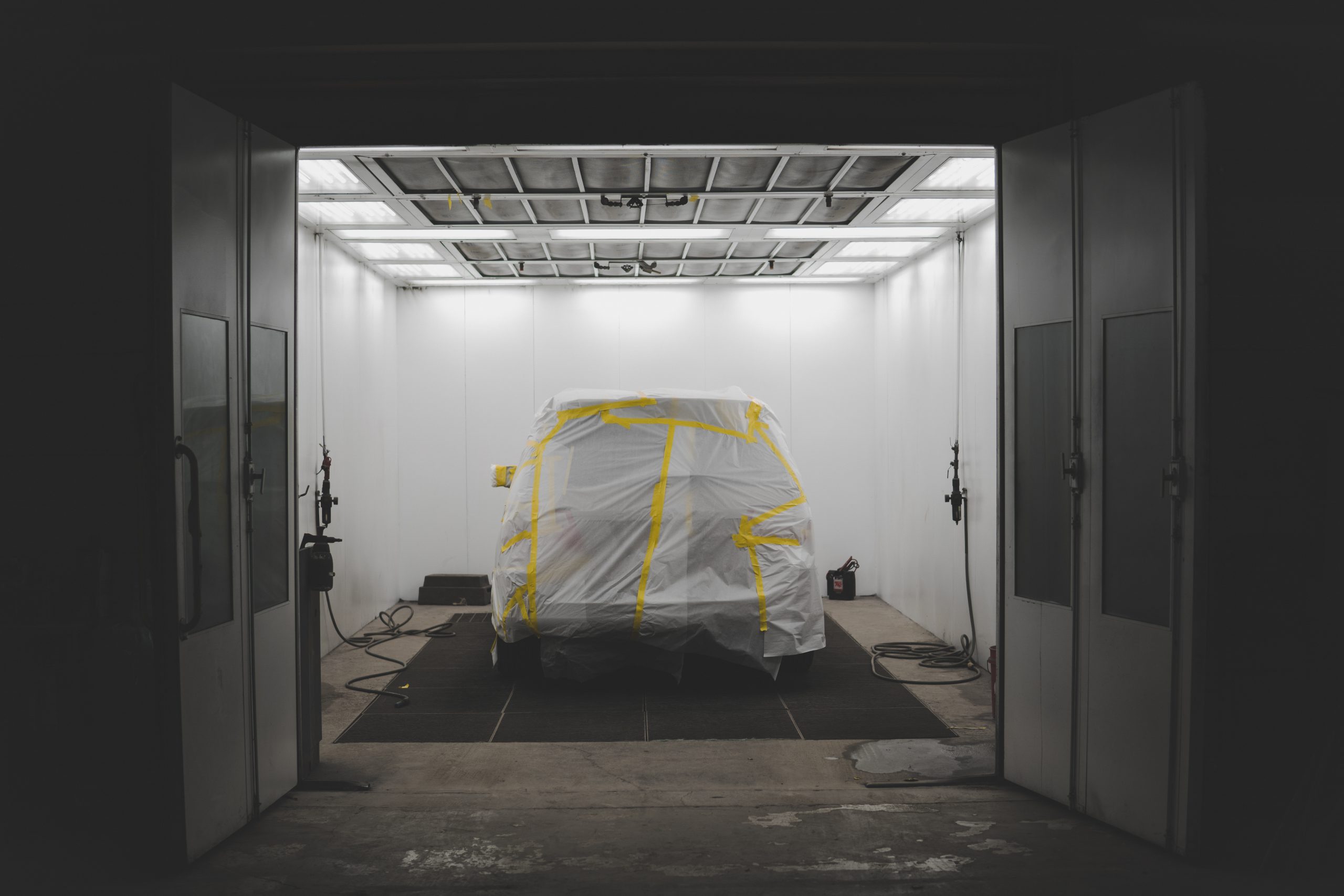 Vehicle covered with a white sheet and yellow tape in a car service garage